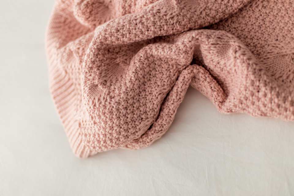 peach colored knit throw on white countertop
